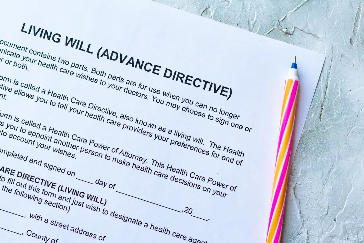 A close-up of a living will (advance directive) document on a textured surface with a colorful pen beside it.
